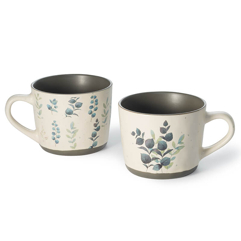 Tazze Amria L'eucalipto è un trend in floristica e moda. Questa tazza in ceramica da 0,35 l, con foglie di eucalipto e dettagli eleganti, è perfetta per tè, caffè o cioccolata. Il manico ergonomico la rende comoda e pratica per l'uso quotidiano.