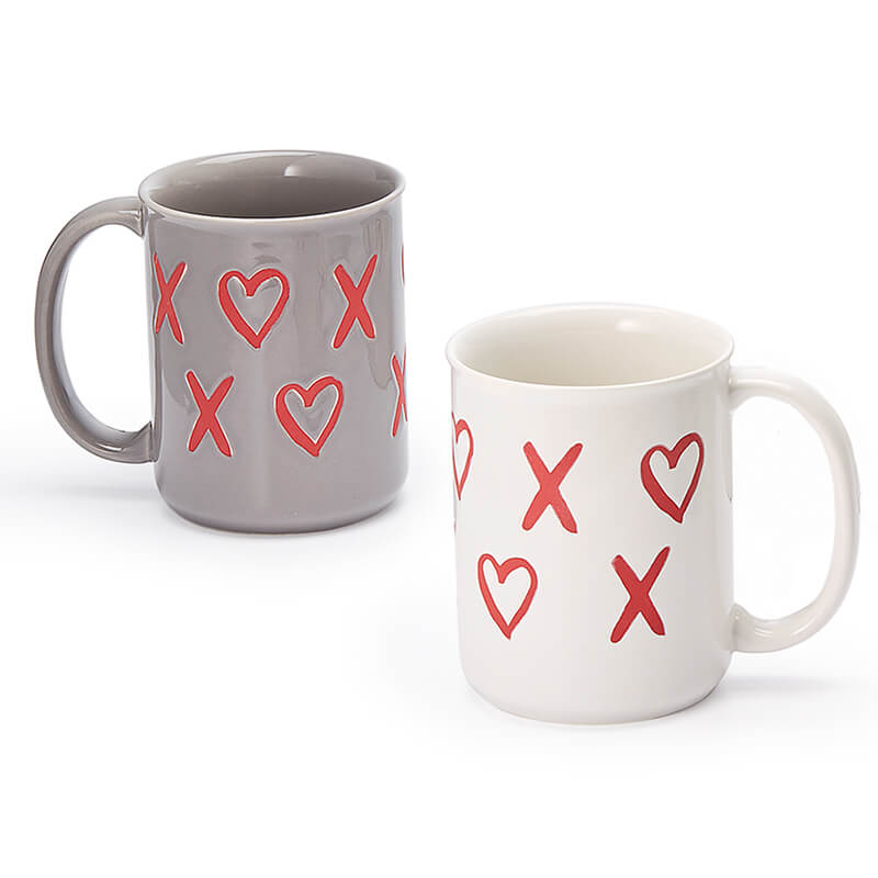 coppia-tazze-mabelle-trentino-erbe Mabelle: due tazze in ceramica, grigia e bianca, con il design "XOXO" a forma di cuore. Dipinte a mano, lavabili in lavastoviglie e adatte al microonde. Perfette per un regalo affettuoso!