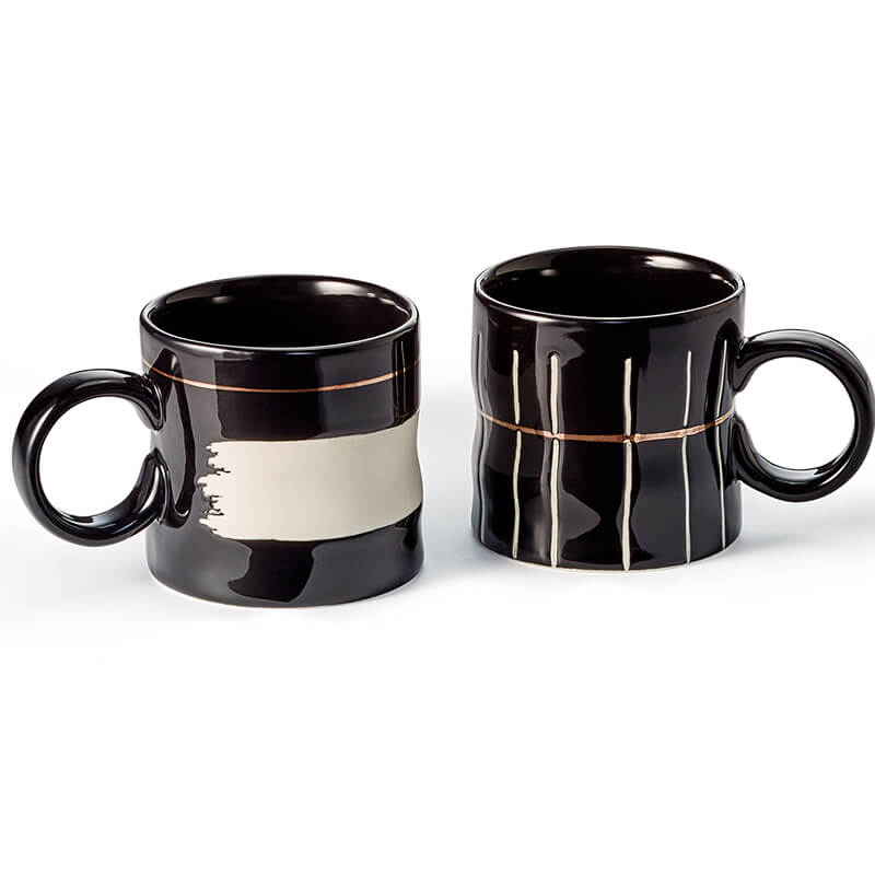 Koro: coppia di tazze in ceramica da 0,3 litri, con finitura lucida nera, dettagli bianchi opachi e accenti dorati. Superficie ondulata per un tocco unico e piacevole. Eleganza senza tempo per ogni occasione.